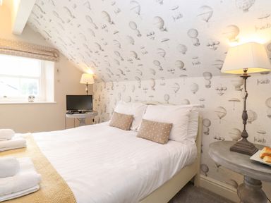 A bedroom with a bed pillows bedside tables lamps a small TV and a window at Church View in Grange-Over-Sands