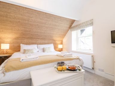 A bedroom with a double bed bedside tables with lamps a window and breakfast on a tray at Church View in Grange-Over-Sands