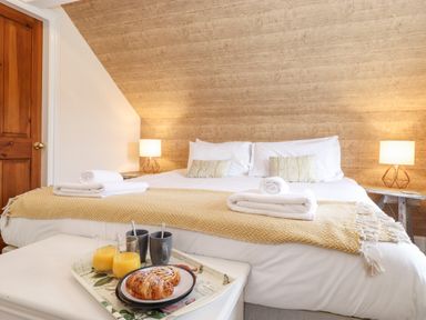 A bedroom with a large bed two bedside tables with lamps and a tray with croissants orange juice and mugs at Church View in Grange-Over-Sands