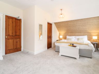 A bedroom with a large bed two wooden doors and a white chest at Church View in Grange-Over-Sands