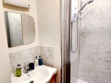 A bathroom with a sink and mirror next to a shower at Cranford House in Keswick
