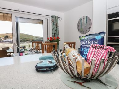 A kitchen with a bottle and snacks on the counter at 4 Burgh Island Causeway Bigbury