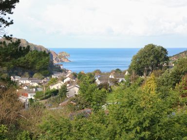 A coastal village with houses and trees overlooking the sea at Linden View in Combe Martin