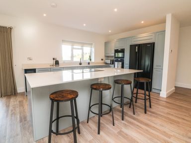 A kitchen with an island and four stools next to a window at Linden View Combe Martin