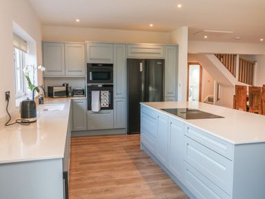 A kitchen with light blue cabinets white countertops and wooden flooring at Linden View in Combe Martin