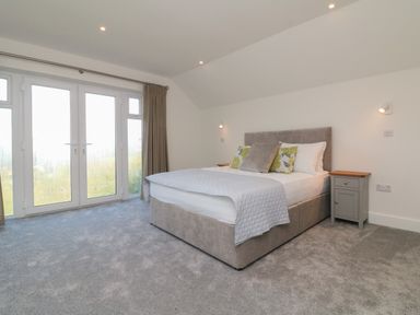 A bedroom with a bed two bedside tables and a large window at Linden View in Combe Martin
