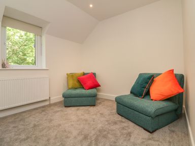 A room with two teal chairs with colorful cushions near a window at Linden View in Combe Martin