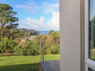 A view of green landscape trees hills and sea beyond from a garden with glass railing at Linden View in Combe Martin