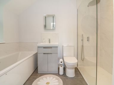 A bathroom with a bathtub sink vanity toilet shower and a round rug at Linden View in Combe Martin