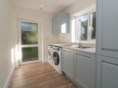 A utility room with a washing machine dishwasher sink window and cabinets at Linden View in Combe Martin