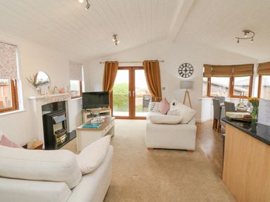 A living room with sofas a fireplace a coffee table and a dining area at Serenity Sunset in Ilfracombe