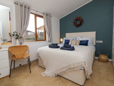 A bedroom with a double bed next to a window and a wicker chair at Serenity Sunset in Ilfracombe