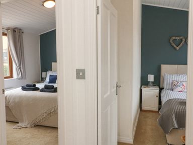 Two bedrooms with beds bedside tables and lamps separated by a wall at Serenity Sunset in Ilfracombe