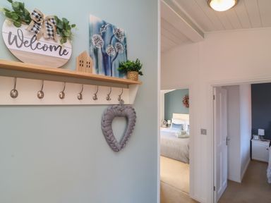 A wall with hooks and decorations next to doorways leading to bedrooms at Serenity Sunset in Ilfracombe