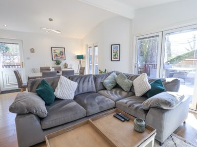 A living room with a gray sofa and cushions next to a dining table and chairs at Tranquil Waters Lakeside 16 White Cross Bay near Windermere