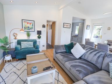 A living room with a grey couch a teal armchair and a white coffee table at Tranquil Waters in Lakeside 16 White Cross Bay near Windermere