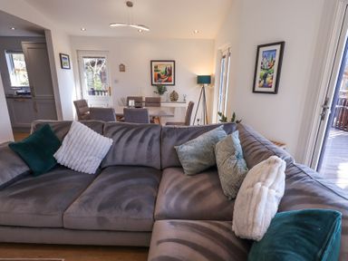 A gray sectional sofa with cushions in a living room next to a dining table and chairs at Tranquil Waters in Lakeside 16 White Cross Bay near Windermere