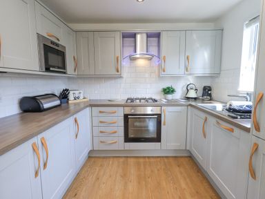 A kitchen with grey cabinets wooden handles appliances and wooden floor at Tranquil Waters in Lakeside 16 White Cross Bay near Windermere
