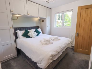 A bedroom with a double bed mattresses in built cupboards and a wooden door at Tranquil Waters Lakeside 16 White Cross Bay near Windermere