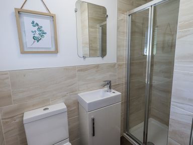 A bathroom with a toilet sink and shower with glass doors at Tranquil Waters in Lakeside 16 White Cross Bay near Windermere
