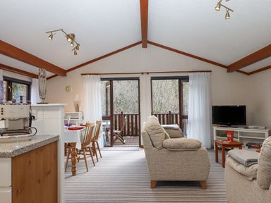 A living room with dining table chairs sofa television and kitchen counter at Teign River Retreat in Drewsteignton near Moretonhampstead