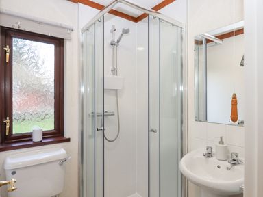 A bathroom with a shower cubicle toilet sink and frosted window at Teign River Retreat in Drewsteignton near Moretonhampstead