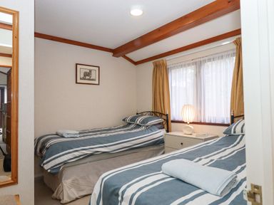 A bedroom with two single beds a nightstand with lamp and window with curtains at Teign River Retreat Drewsteignton near Moretonhampstead