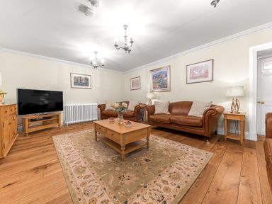 A living room with brown leather sofas wooden coffee table and television at Gate House in Coniston