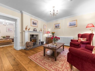 A living room with red armchairs a wooden coffee table and a fireplace at Gate House in Coniston