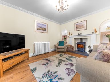 A living room with a fireplace armchair sofa television and a rug at Gate House in Coniston