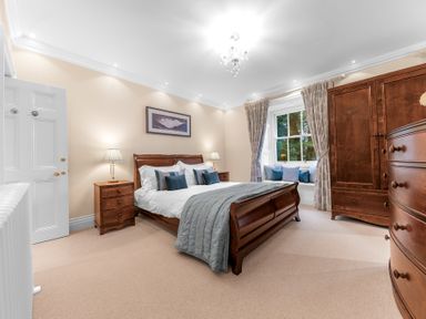 A bedroom with a bed nightstands a window with cushions and wooden wardrobes at Gate House in Coniston