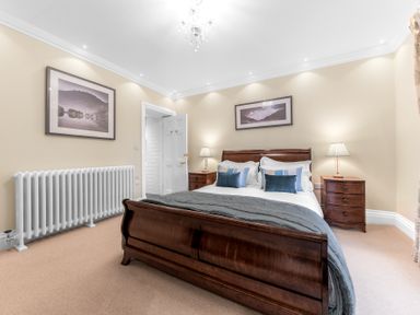 A bedroom with a wooden bed and two wooden bedside tables with lamps at Gate House in Coniston