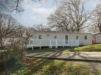 A beige mobile home with white railings and steps in a wooded area at 15 Rosewood Great Thorness near Northwood Isle Of Wight