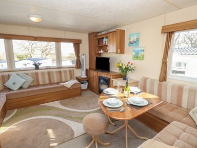 A living area with a dining table set for four a television and cushioned seating at 15 Rosewood Great Thorness near Northwood Isle Of Wight