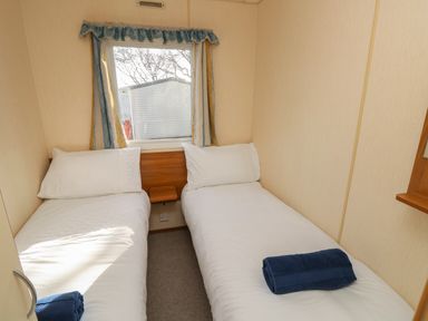 A bedroom with two single beds and a window between them at 15 Rosewood in Great Thorness near Northwood Isle Of Wight