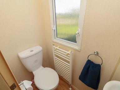 A small bathroom with a toilet window towel radiator and blue towel at 15 Rosewood Great Thorness near Northwood Isle Of Wight