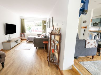 A living room with a gray sofa and a wall-mounted TV at Mermaid Cottage in Wakeham Portland