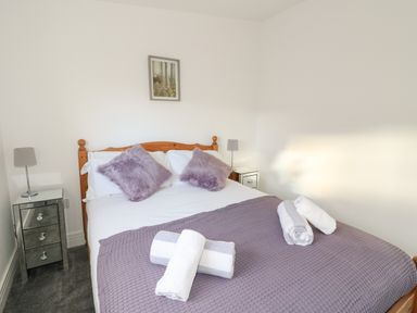 A bedroom with a wooden bed frame pillows and towels on the bed at Osprey View Lodge & Hot Tub in Aberfeldy