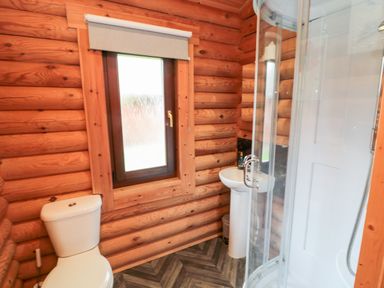 A bathroom with a toilet sink and shower in a wooden log cabin at 10 Water's Edge Morpeth near Felton
