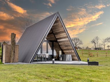 An A-frame cabin with outdoor seating and wooden walls on a grassy area at The Tri-Pod in Pantcefn near Llanarth