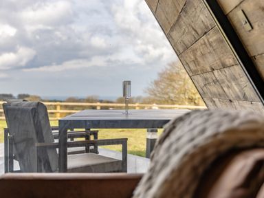 A patio table with two chairs and a glass on the table outside a wooden building at The Tri-Pod in Pantcefn near Llanarth