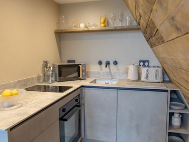 A kitchen with a microwave oven, toaster, kettle, sink, and fruit bowl at The Tri-Pod in Pantcefn near Llanarth