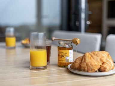 A table with a glass of orange juice honey jar with honey dipper and croissants at The Tri-Pod in Pantcefn near Llanarth