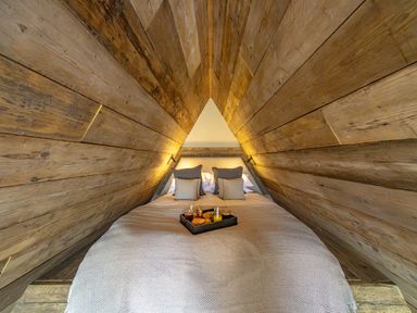 A triangular attic bedroom with wooden walls a double bed and a breakfast tray at The Tri-Pod in Pantcefn near Llanarth