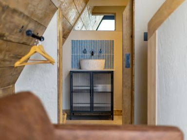 View of a bathroom sink with blue tile backsplash and a cabinet under the sink at The Tri-Pod in Pantcefn near Llanarth
