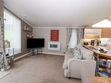 A living room with a sofa cushions television and shelves at No.7 Skiddaw View in Moota near Aspatria