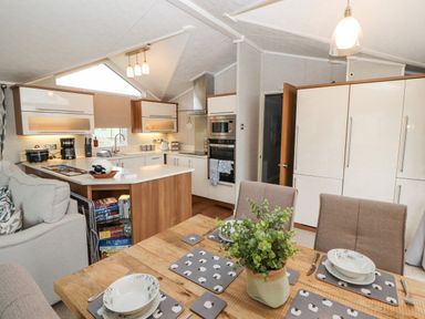 A kitchen and dining area with wooden table set with plates and a plant at No 7 Skiddaw View in Moota near Aspatria