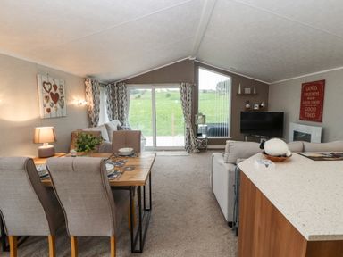 A living room with a dining table chairs couches and a television at No.7 Skiddaw View in Moota near Aspatria