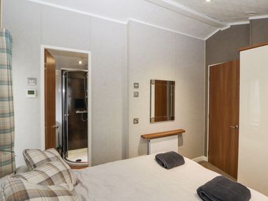 A bedroom with a bed towel a mirror and an en suite shower at No 7 Skiddaw View in Moota near Aspatria
