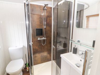 A bathroom with a toilet shower with glass door and a sink at No.7 Skiddaw View in Moota near Aspatria